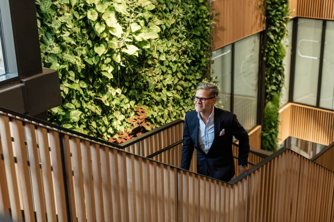 Interiörbild med en soffa och bord i förgrunden och en vägg och restaurang i bakgrunden. 