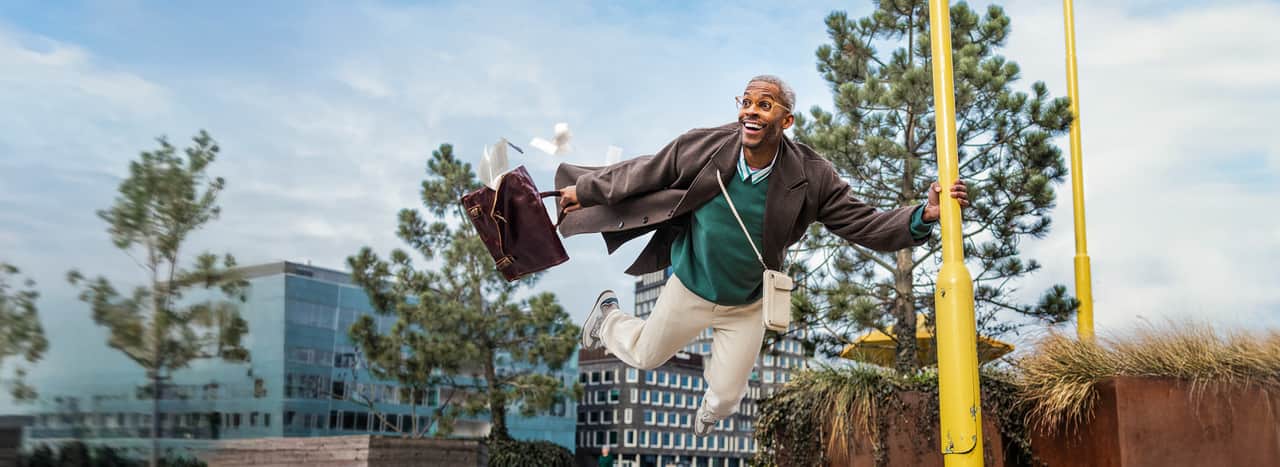 Person lyfter från marken och är tvungen att hålla sig fast i en lyktstolpe.