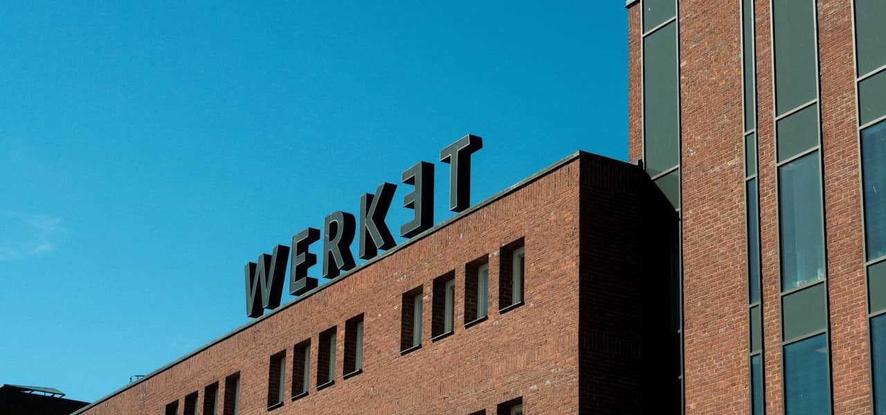 Fasadbild på tegelhuset med fokus på en takskylt där det står Werket