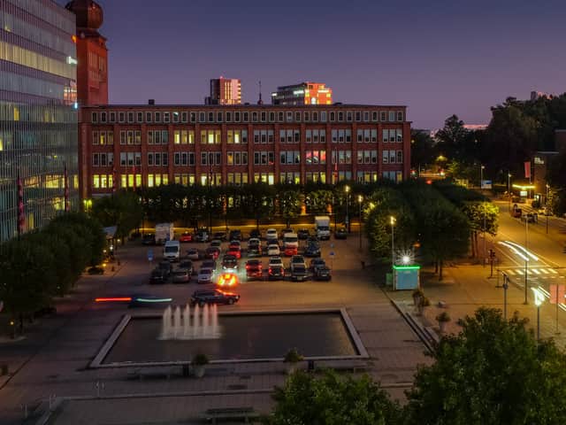 Kvällsbild med vy över ett torg och omgivande fastigheter.