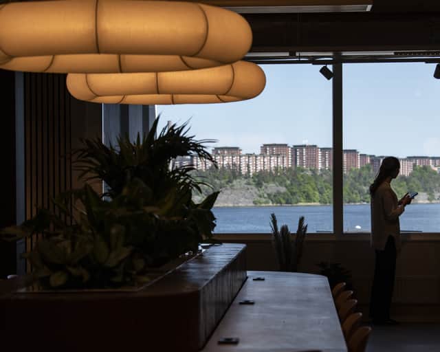 Interiörbild i motljus med person som står vid ett fönster.