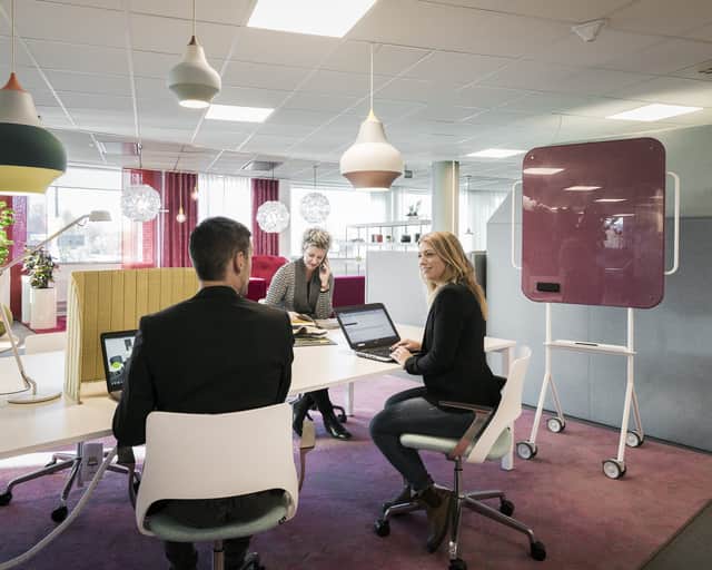 Människor vid skrivbord i kontorslokal.