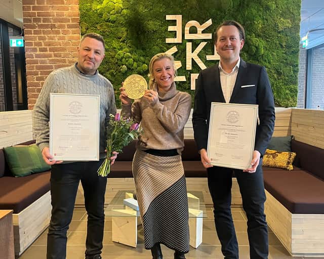 Tre anställda personer på Castellum håller i priset, diplom och blombukett