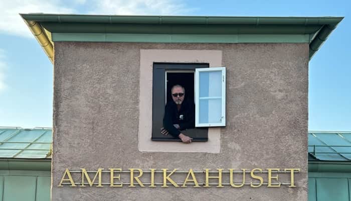 En man tittar ut genom ett fönster på en byggnad.