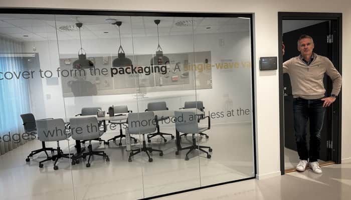 En man står i en dörröppning brevid en glasvägg.