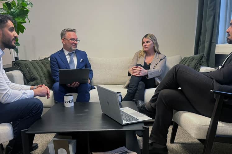 Fyra personer sitter runt ett kaffebord och har möte. 