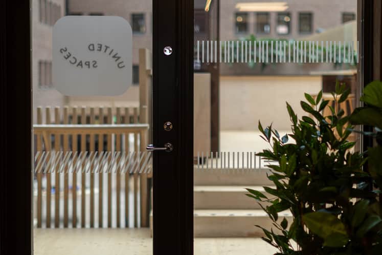 En dörr med texten United Spaces som vätter ut mot en innergård