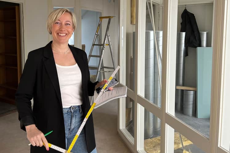 Kvinna som står med tumstock i handen och mitt i en ombyggnation av en lokal