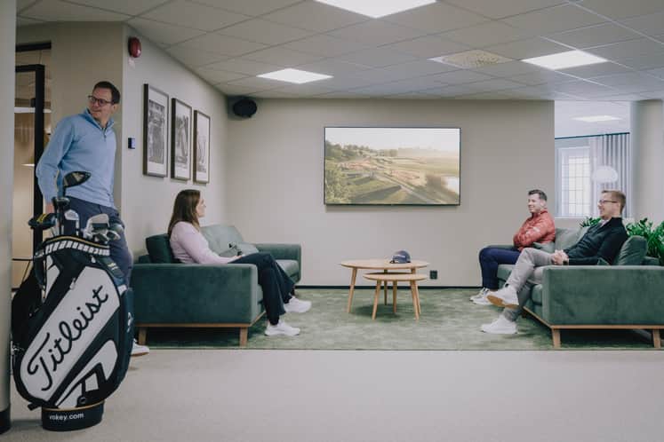 Fyra personer sitter i en soffgrupp, i förgrunden syns ett golfset. 