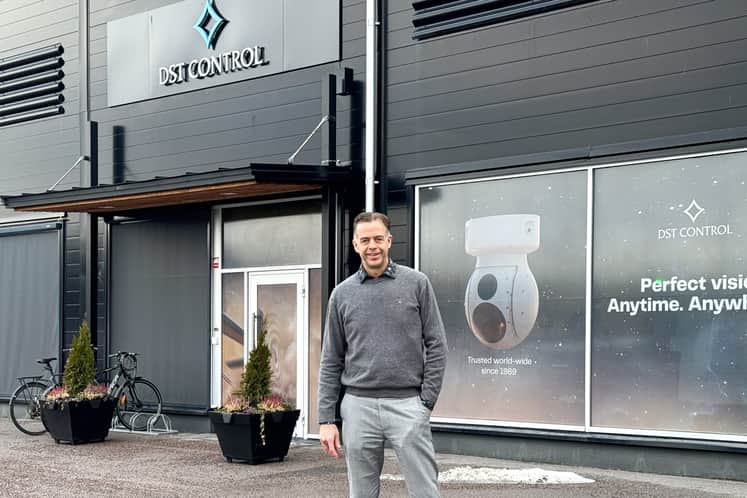 Man klädd i gråa kläder som står utomhus framför entrén till företaget