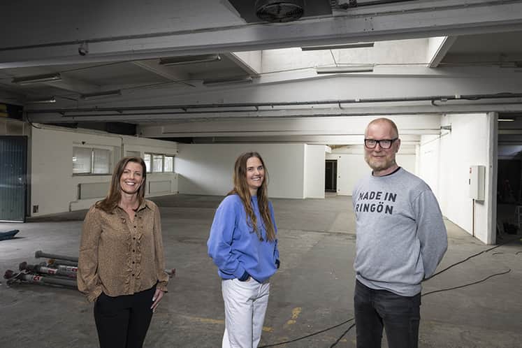 Tre personer står inne i lokalen.