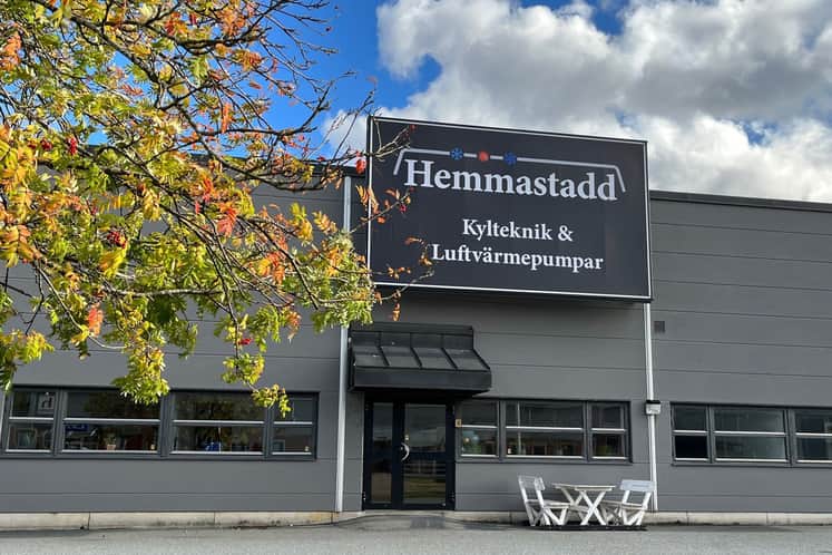 Grå fastighet med svart skylt ovanför där det står Hemmastadd