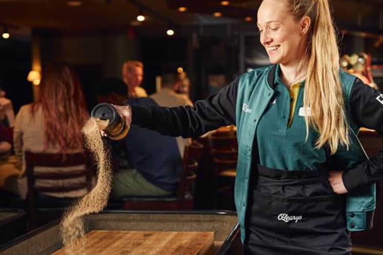 Bartender som häller upp sand på en shuffleboard.