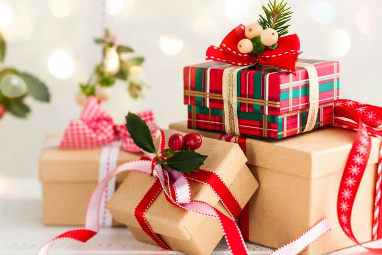 Inslagna julklappar med snören och gröna kvistar i bakgrunden