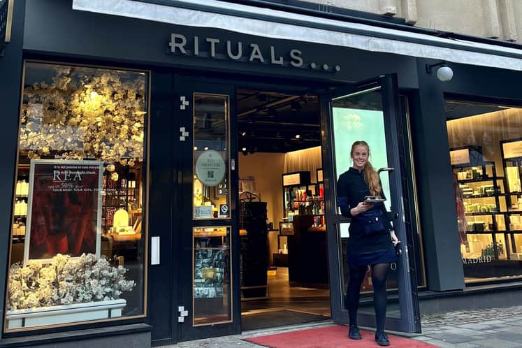 En anställd person på Rituals går ut genom entredörren på en röd matta