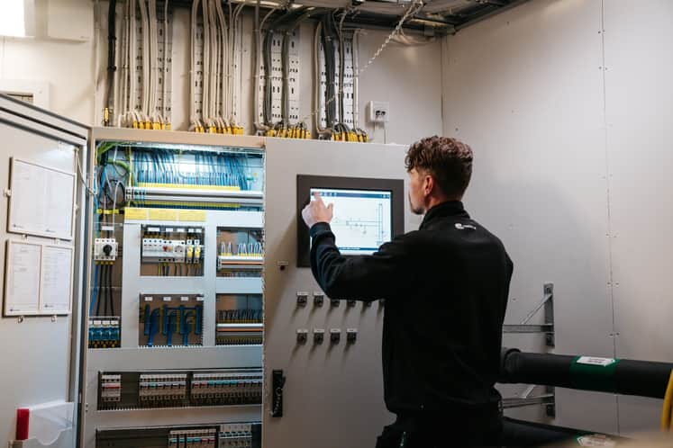 Person står framför ett styrskåp för ventilation.